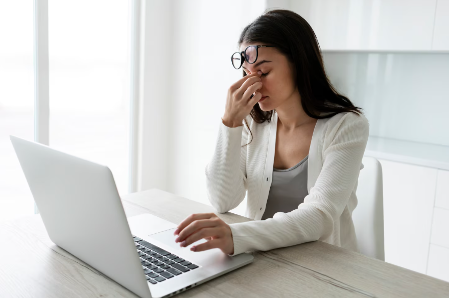 Woman experiencing privacy fatigue while reviewing information on laptop