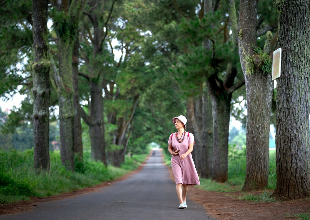 Woman walking on quiet tree-lined path illustrating how slow habits reduce burnout